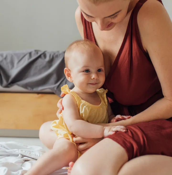 A mother gently cradles her baby in her arms.